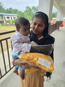 Flood survivor with her baby receiving clothing for both